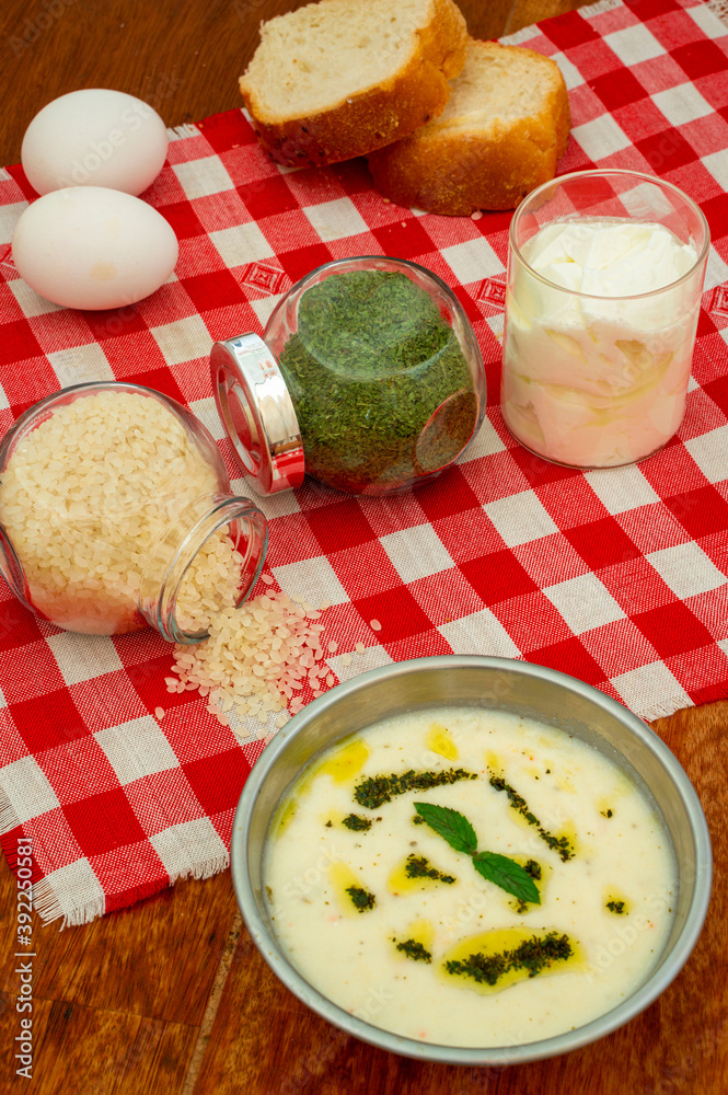Traditional Turkish soup with yoghurt, rice and dried mint on wooden background and red and white table cloth. Traditional Turkish soup with yoghurt, rice and dried mint on wooden background and red and white table cloth.