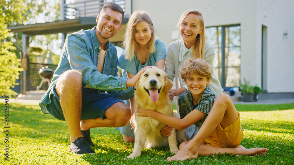 Smiling Beautiful Family of Four Posing with Happy Golden Retriever Dog on the Backyard Lawn. Idyllic Family Have Fun with Loyal Pedigree Dog Outdoors in Summer House Backyard.