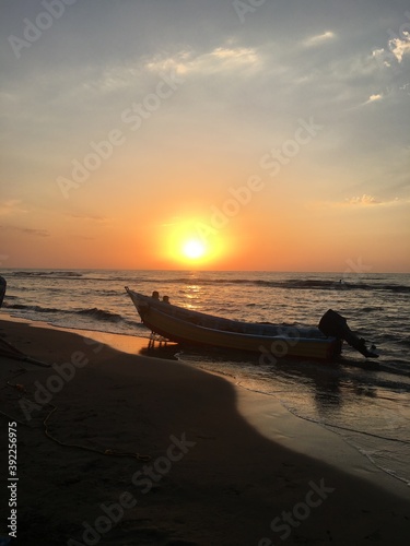 Sunset at the beach with a boat floating on the seawater