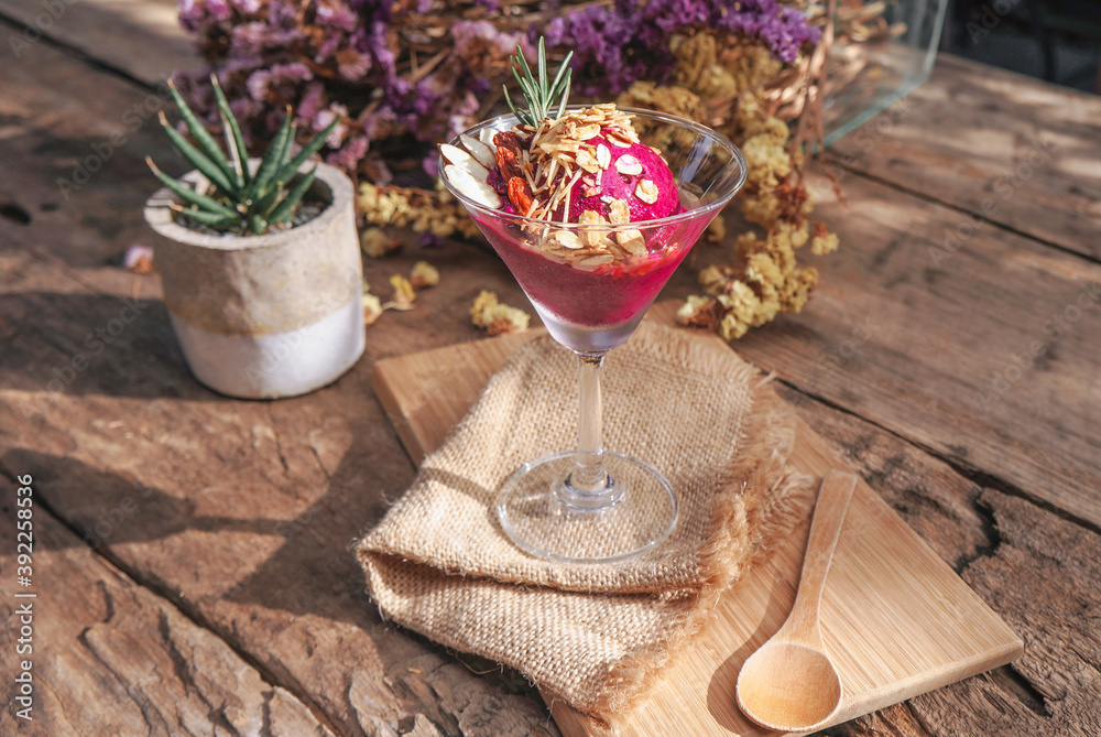 Purple ice cream with cereal on top in a glass placed on a wooden table. Purple ice cream with cereal on top in a glass placed on a wooden table.
