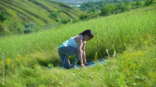 Young woman doing yoga in green summer meadow