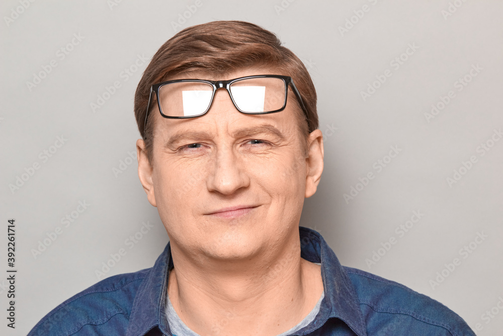 Portrait of happy blond mature man with glasses raised on forehead