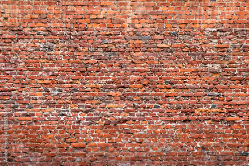 Foto Brick wall made of old crumbling red bricks falling out.