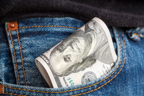large wad of hundred-dollar bills protrudes from pocket of jeans. Concept of cash bribery. All money earned is all given for credit.