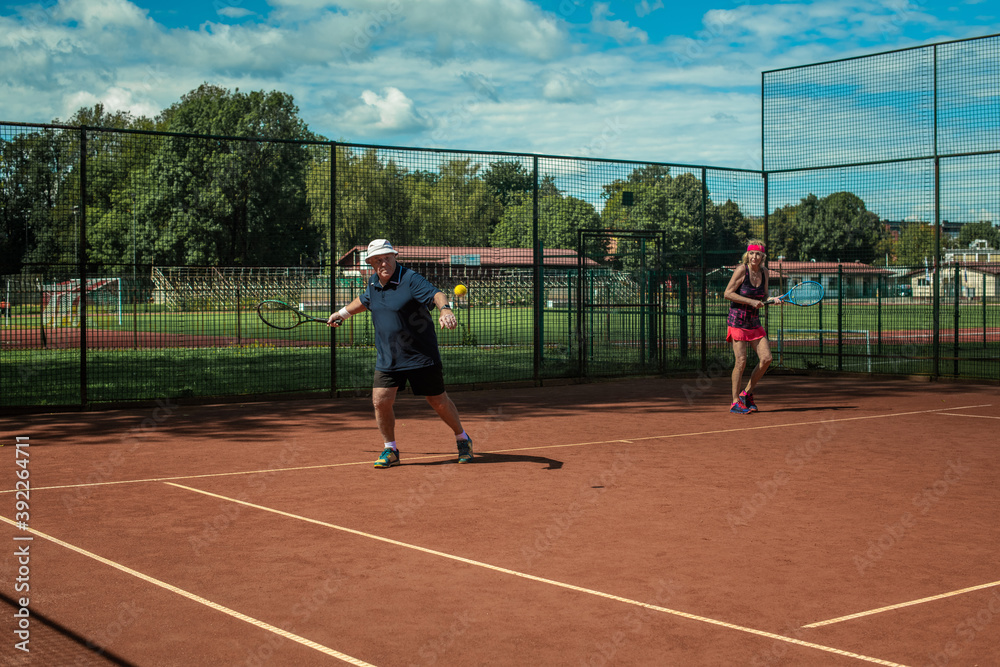 Fototapeta premium Silhouette of a active senior Caucasian couple in sportswear playing tennis