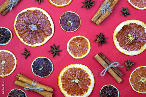 Cinnamon sticks, star anise and dry oranges and lemons top view. Spice pattern for mulled wine. Dry crumbs of orange, cinnamon and anise on a red background.