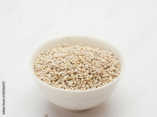 Unhulled barley in white bowl on white background  © papii