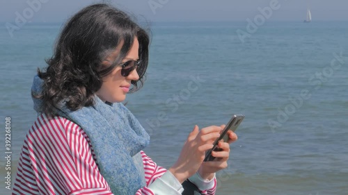 caucasian woman on beach texing on her smartphone photo