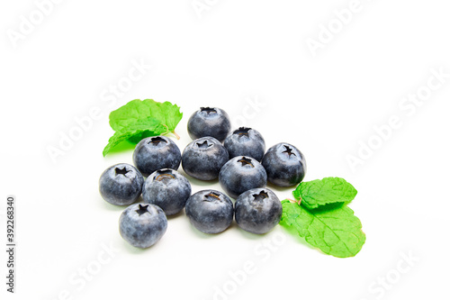 Group of blueberries together with some mint leaves on a white background