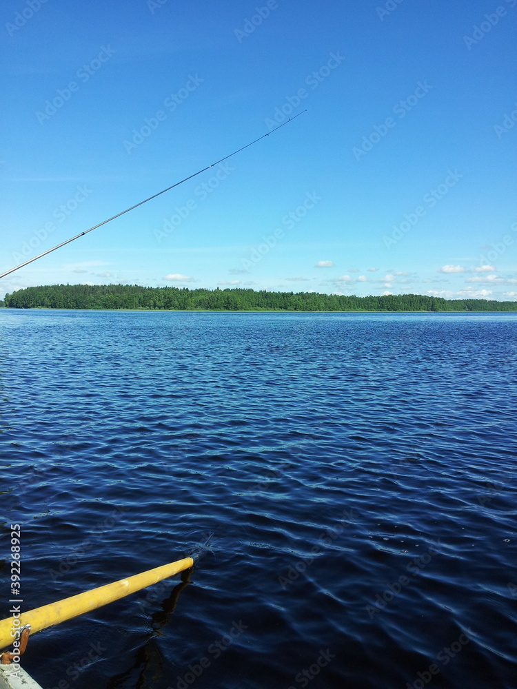Fishing from the boat.
A clear forest lake with clear blue water. Summer day by the lake. The sky is light blue and clear. On the other side of the lake there is a dense forest. Light ripples on the w Fishing from the boat.
A clear forest lake with clear blue water. Summer day by the lake. The sky is light blue and clear. On the other side of the lake there is a dense forest. Light ripples on the w