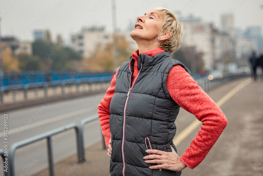 Portrait of active senior woman resting after running through the city during the day. Portrait of active senior woman resting after running through the city during the day.