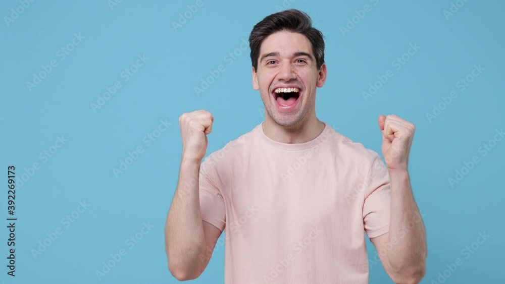 Side profile view of surprised joyful young man 20s years old in beige t-shirt posing isolated on blue background in studio. People lifestyle concept. Turn around camera doing winner gesture say yes Side profile view of surprised joyful young man 20s years old in beige t-shirt posing isolated on blue background in studio. People lifestyle concept. Turn around camera doing winner gesture say yes