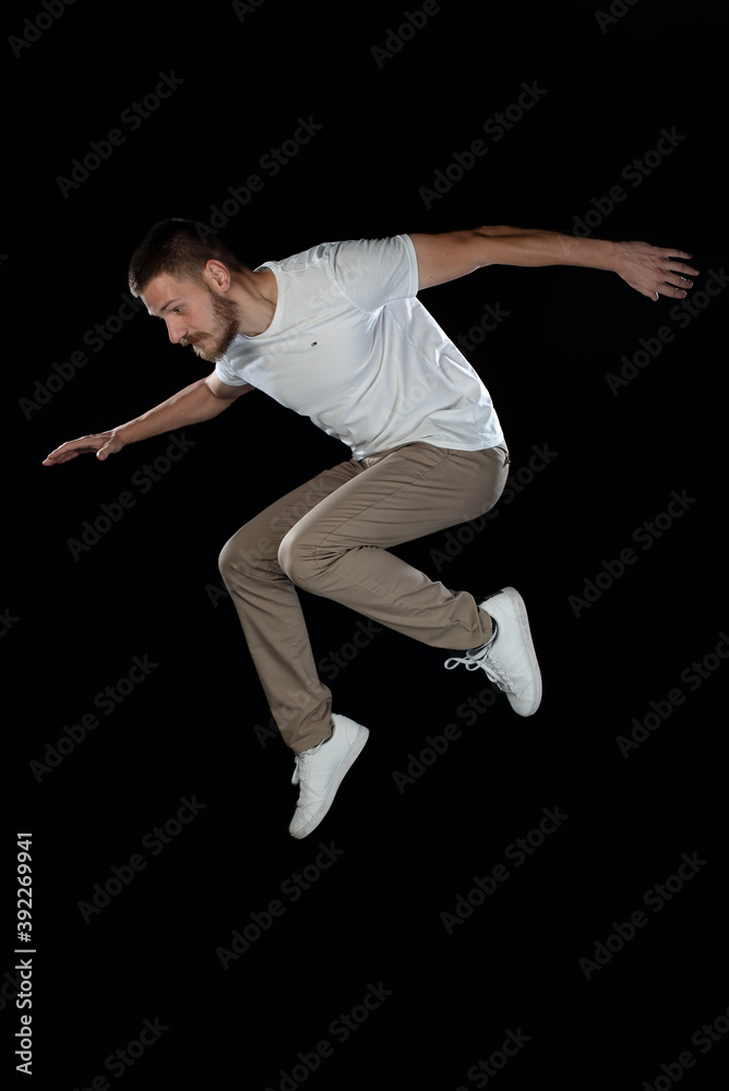 Handsome guy jumping while posing in studio on black background. Isolated
