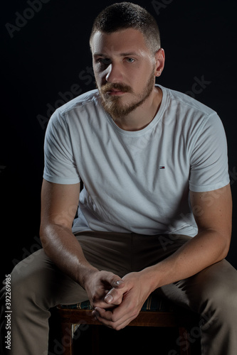 Dramatic portrait of a serious guy while posing in studio on black background. Isolated Depressed face expression