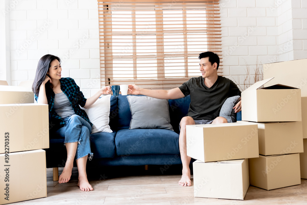 Portrait images of Asian couple, husband and attractive wife, were resting and inviting each other for drink coffee, after helping to move the boxes For moving and relocation New home Portrait images of Asian couple, husband and attractive wife, were resting and inviting each other for drink coffee, after helping to move the boxes For moving and relocation New home