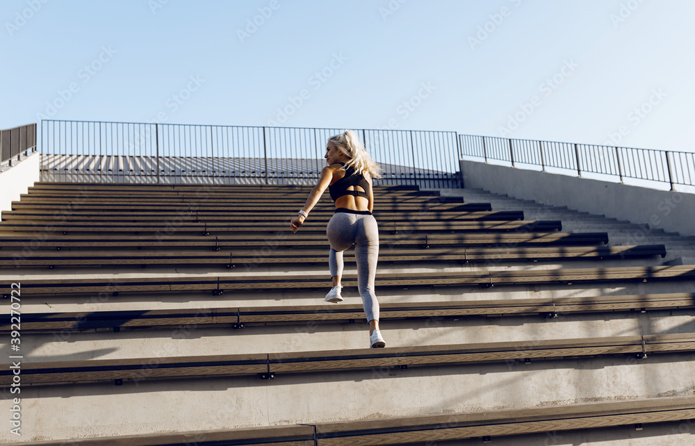 Full length of beautiful young athletic woman, in sportswear, running during outdoor workout on city stairs Full length of beautiful young athletic woman, in sportswear, running during outdoor workout on city stairs