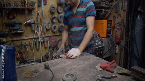 A locksmith processes a wooden part using a grinder 