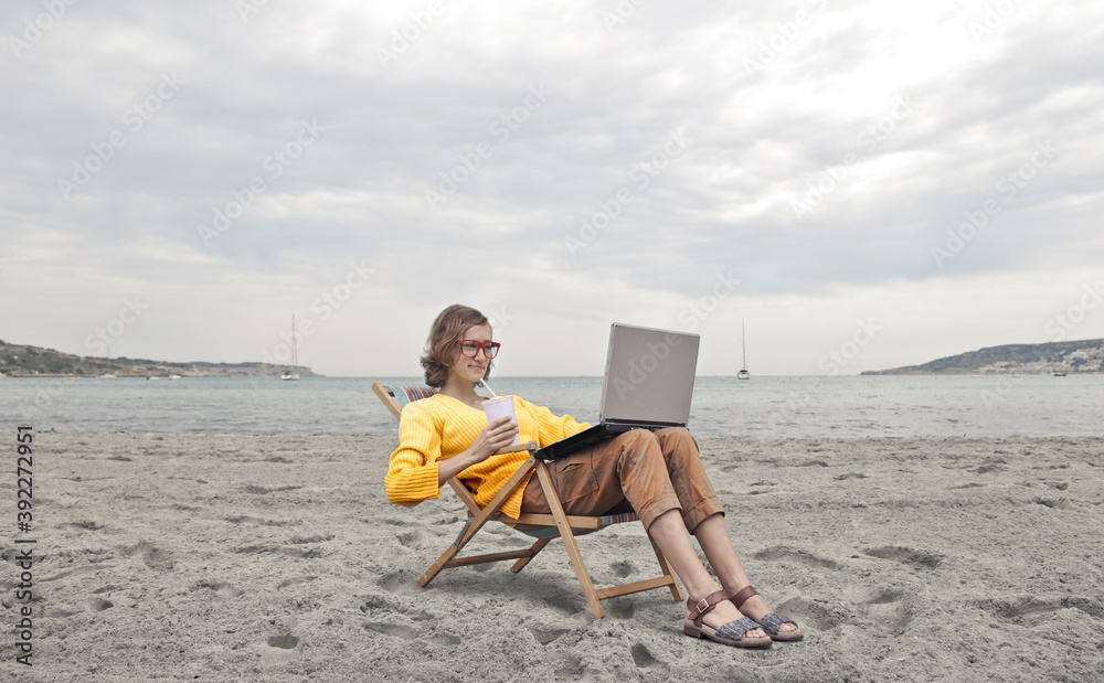 beautiful woman works with a computer at the beach