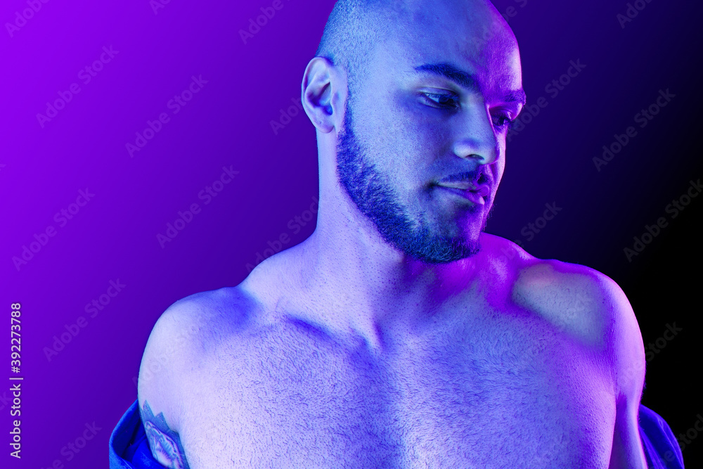 Fototapeta premium Young black man takes off the shirt in neon light