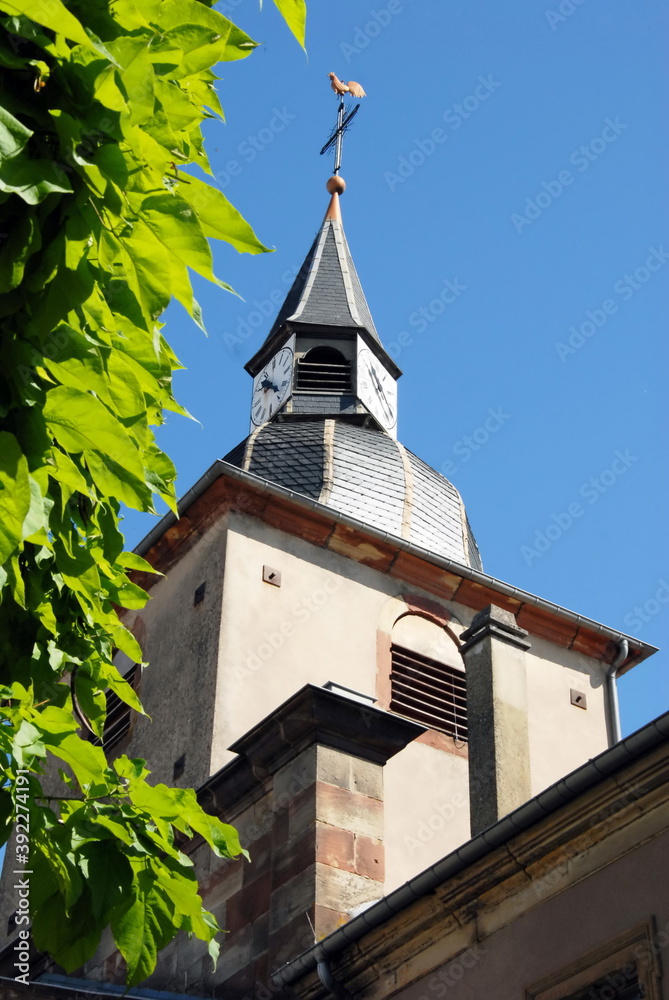Ville de Sarreguemines, clocher ensoleillé d'une église de la ville,  verdure en premier plan, département de la Moselle, France