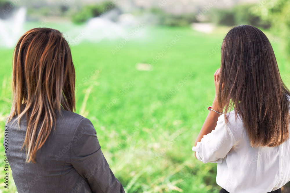 Two business women in front of a field with agriculture irrigation system. Two business women in front of a field with agriculture irrigation system.