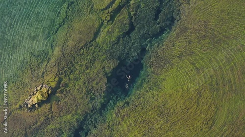 Aerial: Snorkeler swimming in Silfra popular diving / snorkeling fissure in Iceland between Eurasian and North American tectonic plates Thingvellir national park Phenomenal water clarity