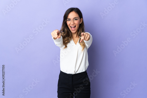 Young caucasian woman isolated on purple background surprised and pointing front