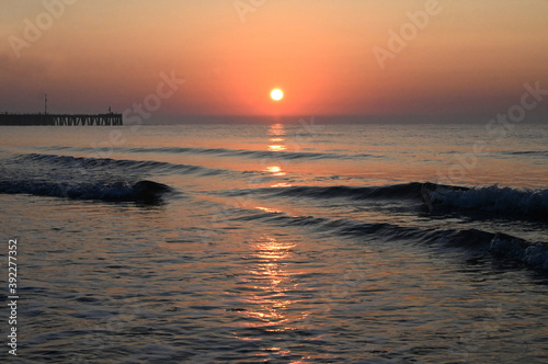 Sunrise over calm sea silhouetting the old derelict harbour wall and groyne, Walberswick, Suffolk photo