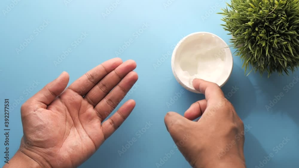 man applying beauty cream onto skin at home top view man applying beauty cream onto skin at home top view