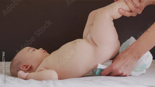 Mom changes diaper baby at night. Beautiful caucasian girl mother changes diaper to her little child. Close-up.