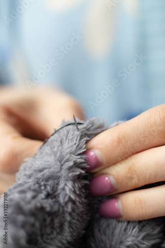 The girl holds a needle in her hands. Sewing. Close up photo.Needlework