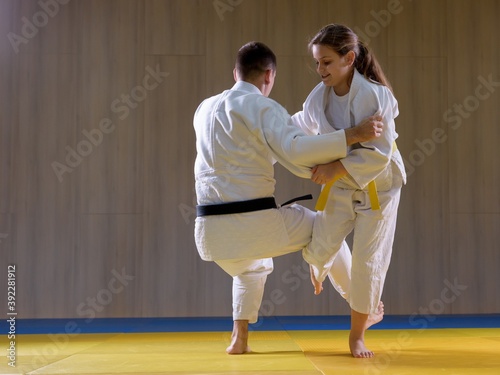 Young judo girl throwing larger male opponent with leg technique