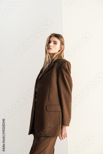 young blonde woman in stylish brown suit looking at camera on white © LIGHTFIELD STUDIOS