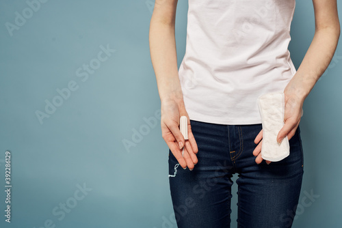 girl with a tampon and a pad in her hands on a blue background hygiene cleanliness menstruation © SHOTPRIME STUDIO