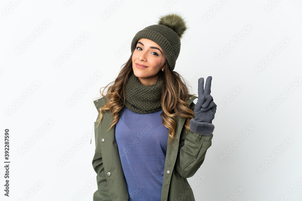 Young girl with winter hat isolated on white background smiling and showing victory sign Young girl with winter hat isolated on white background smiling and showing victory sign