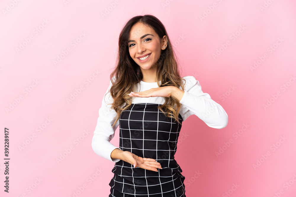 Young caucasian woman isolated on pink background holding copyspace imaginary on the palm to insert an ad Young caucasian woman isolated on pink background holding copyspace imaginary on the palm to insert an ad