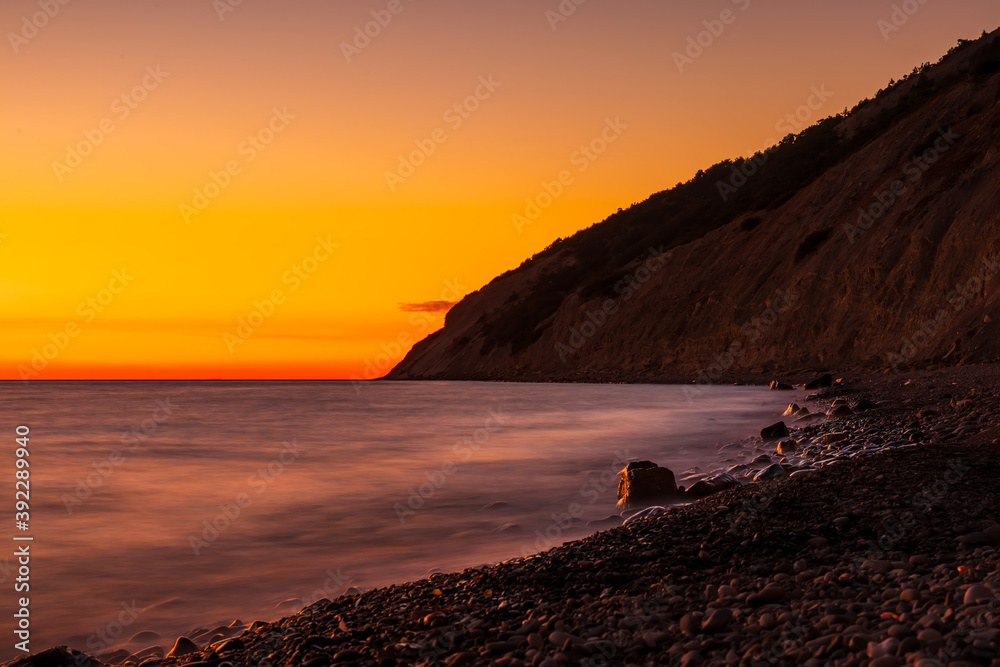 Ocean stone beach with waves at bright sunset Ocean stone beach with waves at bright sunset