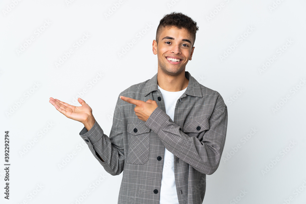 Young brazilian man isolated on white background holding copyspace imaginary on the palm to insert an ad Young brazilian man isolated on white background holding copyspace imaginary on the palm to insert an ad