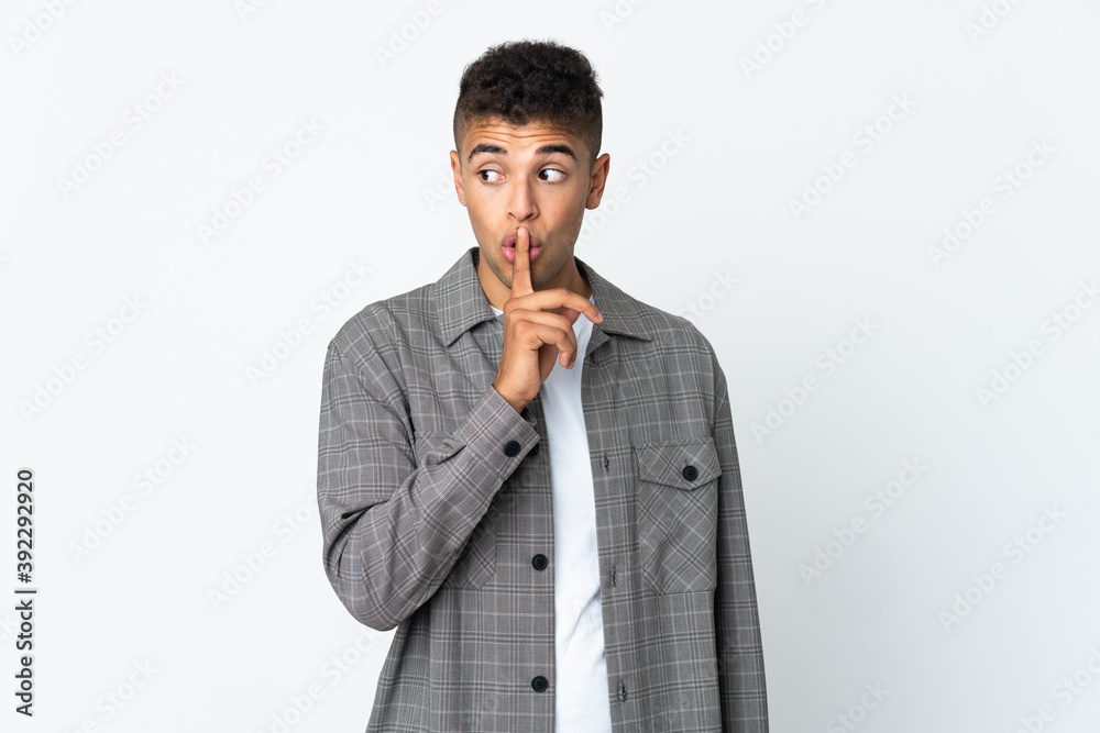 Young brazilian man isolated on white background showing a sign of silence gesture putting finger in mouth Young brazilian man isolated on white background showing a sign of silence gesture putting finger in mouth