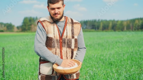 Wallpaper Mural A young peasant man is sowing the field with grain at a village. A farm concept. Torontodigital.ca