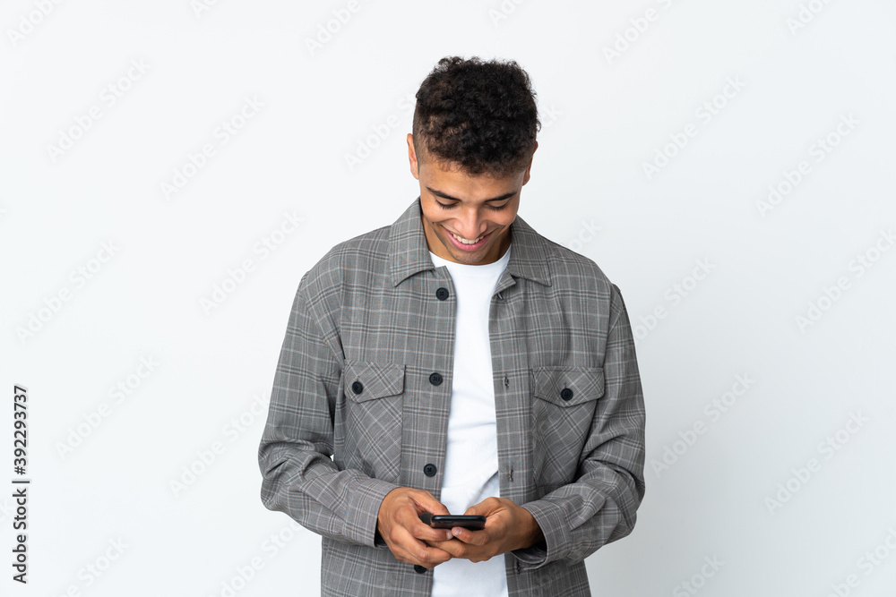 Young brazilian man isolated on white background sending a message with the mobile Young brazilian man isolated on white background sending a message with the mobile