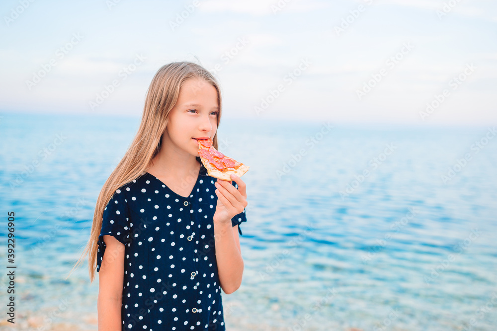Fototapeta premium Happy girl having fun on the beach and eating pizza