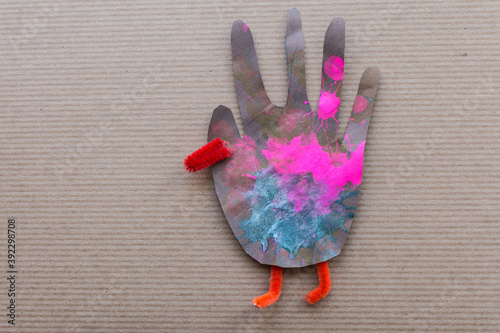 Thanksgiving craft project child's art: hand cutout turkey with bright colors and pipe cleaners