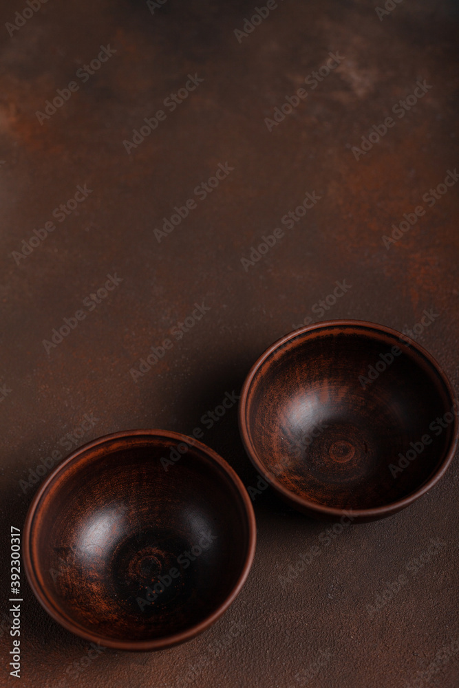 Two dark handmade clay bowls on brown background