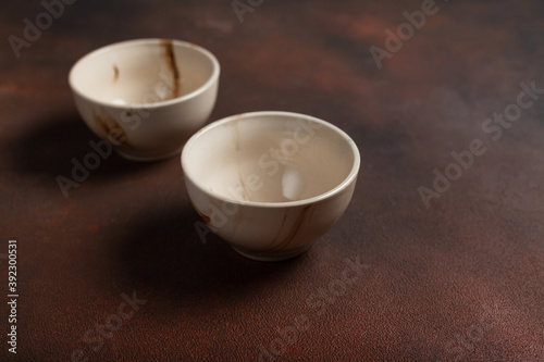 Two light handmade cups on a brown background