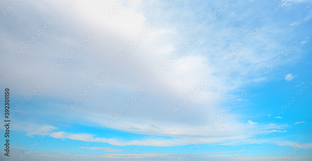 Blue sky and white clouds background - Pillowy clouds cover a blue sky in the background