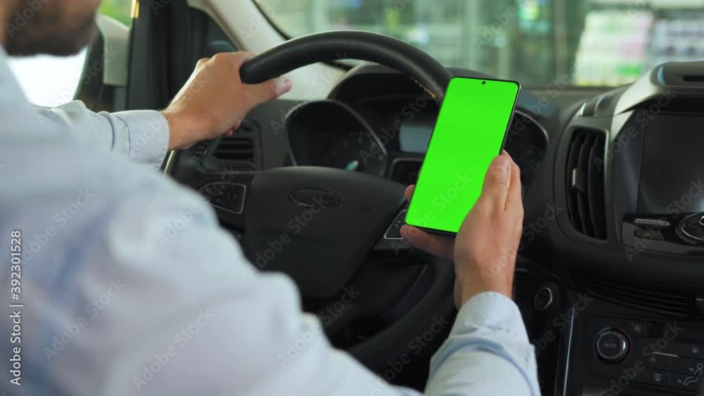 Driver using a smartphone inside the car. Chromakey smartphone with green screen. Auto navigation. Internet addiction