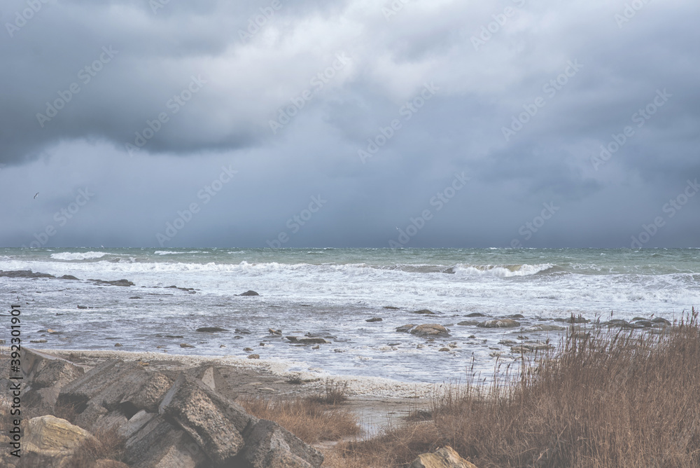 Autumn sea landscape. Rough sea with waves during autumn stormy weather. Dark heavy clouds in the sky. Dark and dramatic storm clouds background. Autumn sea landscape. Rough sea with waves during autumn stormy weather. Dark heavy clouds in the sky. Dark and dramatic storm clouds background.