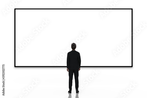 Business man looking at large blank screen or billboard on white background, rear view