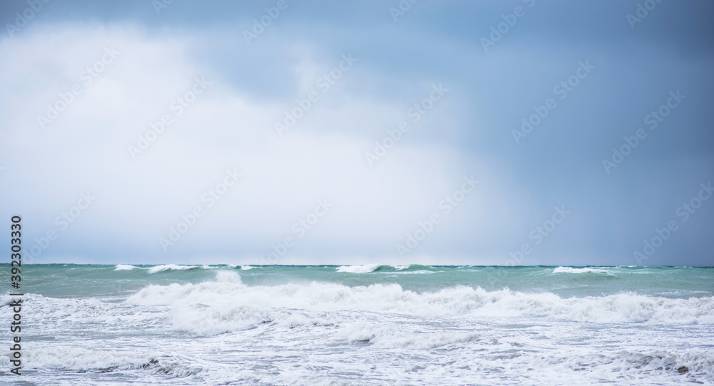 Autumn sea landscape. Rough sea with waves during autumn stormy weather. Dark heavy clouds in the sky. Dark and dramatic storm clouds background.